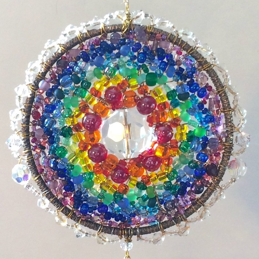 Round pendant comprised of rainbow coloured stones.